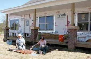 Neighbors lay bricks on a pathway leading up to a partially-constructed home in Shadowlake Village during the community's early days.